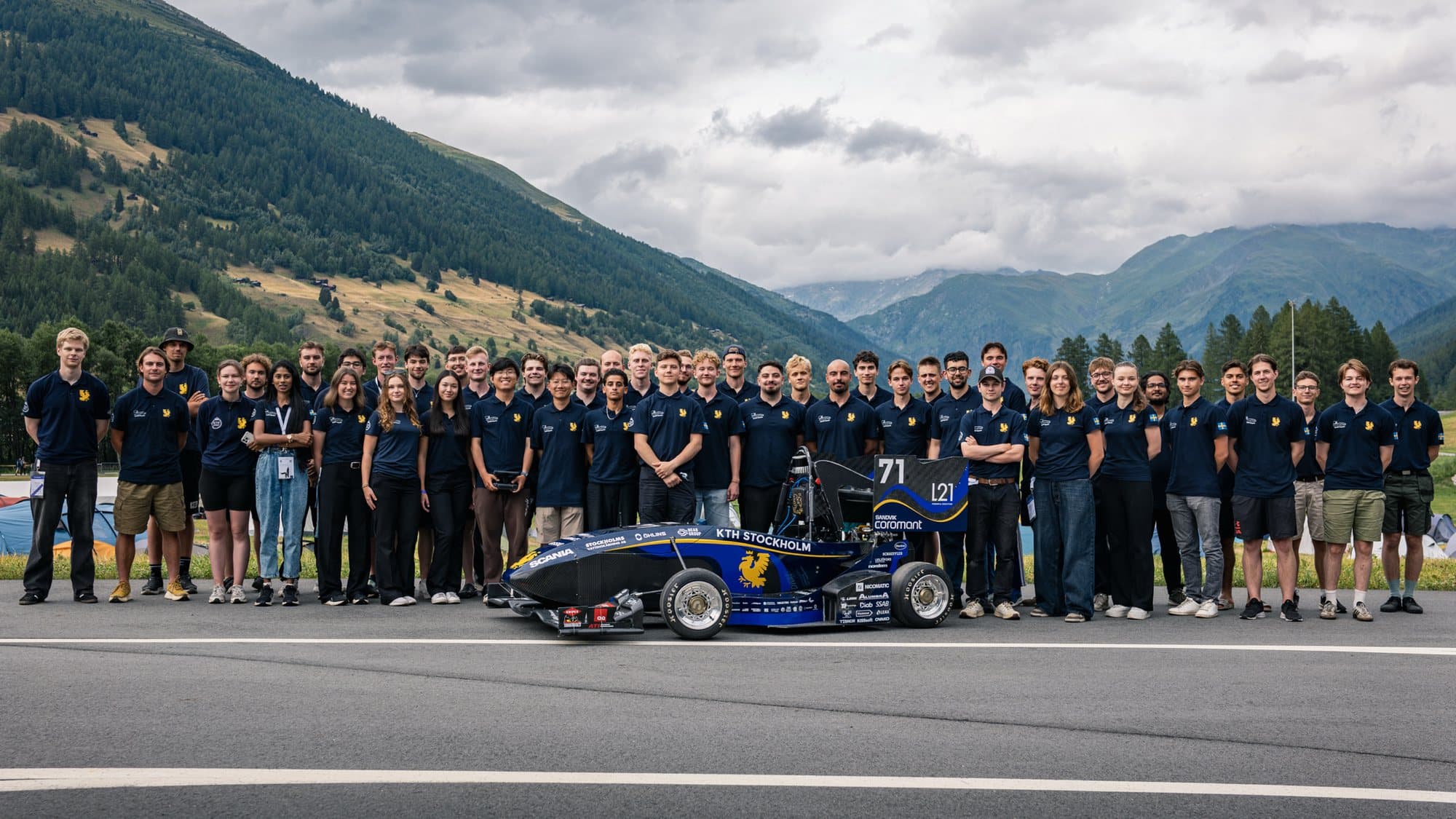 Hela KTH Formula Student, ett fyrtiotal personer, samlade runt bilen framför gröna berg i Schweiz.